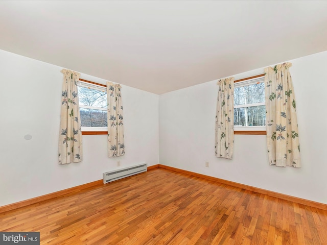 bonus room with a baseboard heating unit, plenty of natural light, and hardwood / wood-style floors