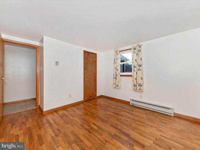 spare room featuring hardwood / wood-style floors and a baseboard heating unit