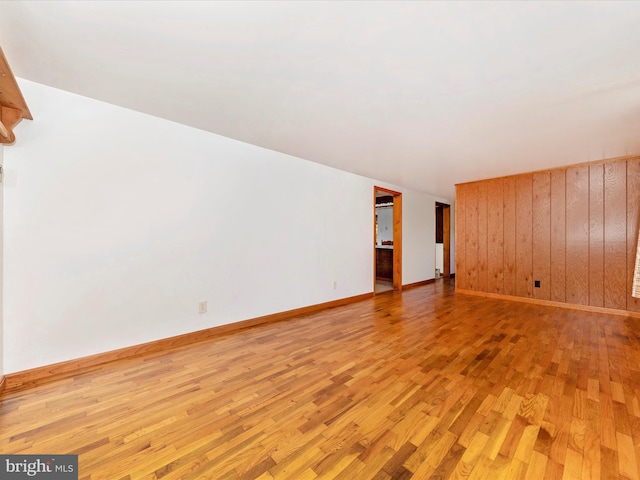 spare room with light hardwood / wood-style flooring and wood walls