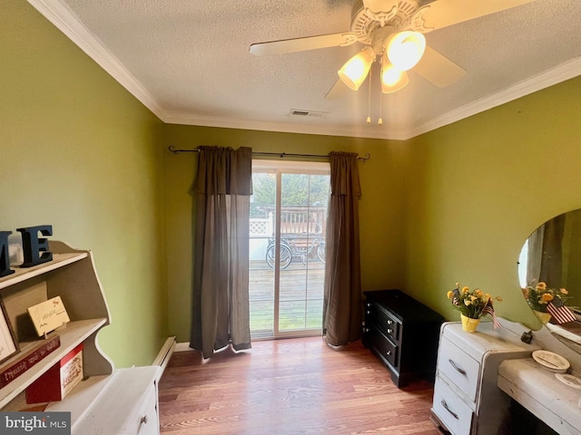 interior space with light wood-type flooring, ornamental molding, a baseboard heating unit, ceiling fan, and a textured ceiling