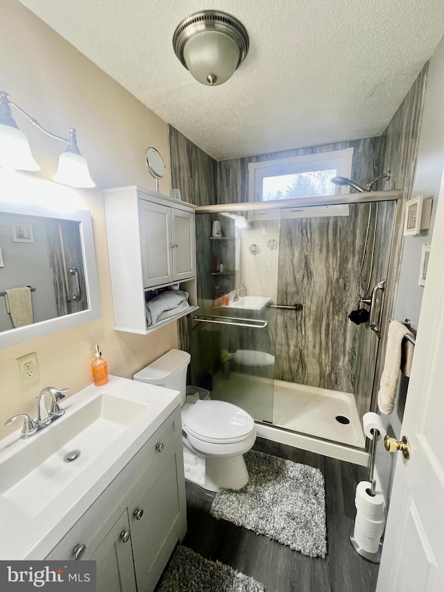 bathroom featuring walk in shower, toilet, a textured ceiling, vanity, and hardwood / wood-style flooring