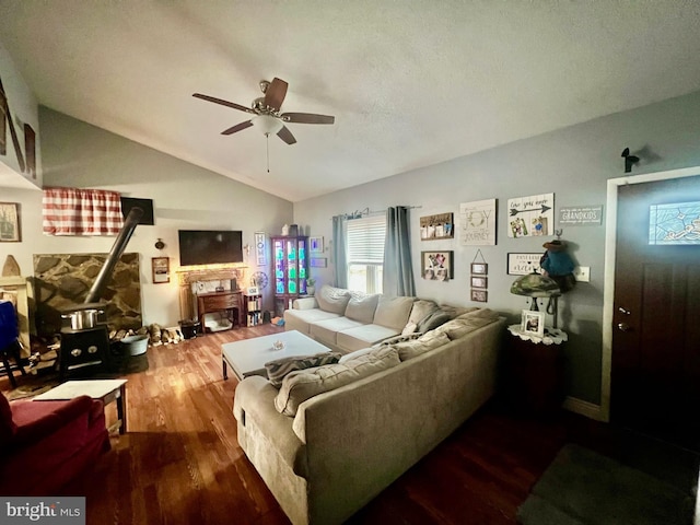 living room with lofted ceiling, hardwood / wood-style flooring, ceiling fan, and a wood stove