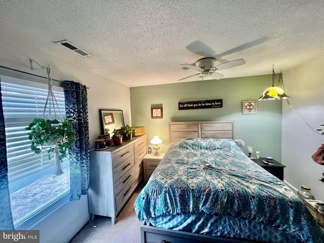 bedroom featuring ceiling fan, light carpet, and a textured ceiling