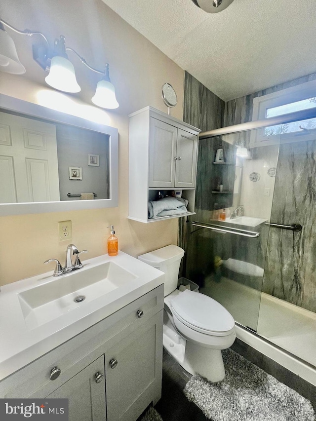 bathroom featuring vanity, a textured ceiling, toilet, and walk in shower