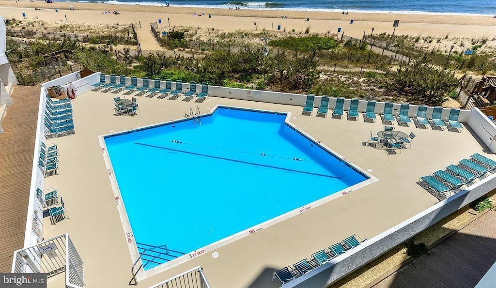 view of swimming pool featuring a water view and a beach view