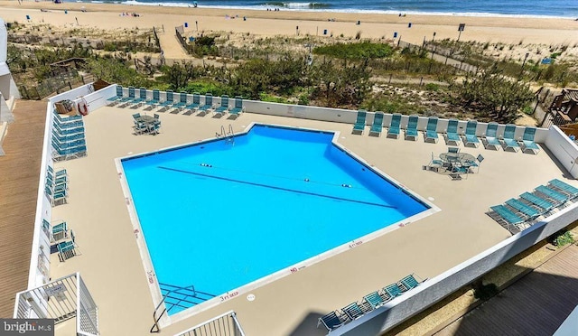 view of swimming pool featuring a water view and a beach view