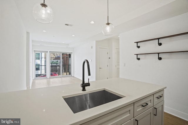 kitchen featuring visible vents, light countertops, a sink, and decorative light fixtures