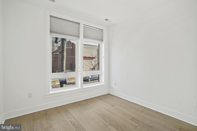 spare room with visible vents, baseboards, and wood finished floors