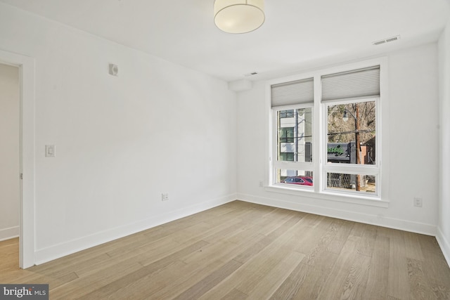 unfurnished room featuring light wood-style floors, visible vents, and baseboards