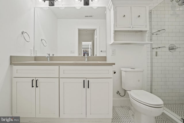 bathroom featuring toilet, a shower stall, double vanity, and a sink