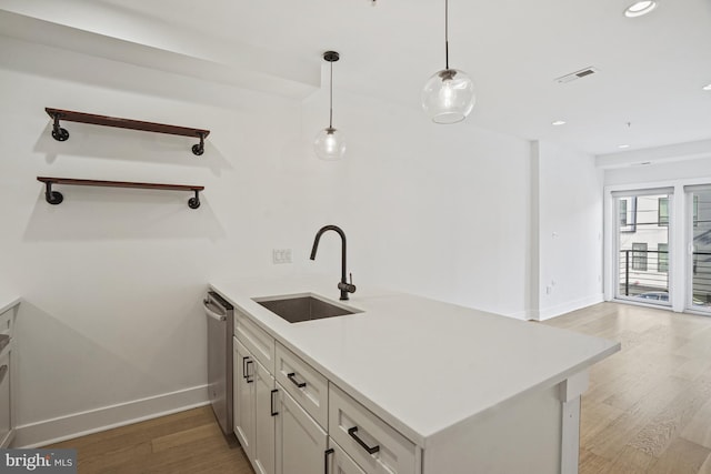 kitchen with light wood finished floors, dishwasher, a peninsula, open shelves, and a sink