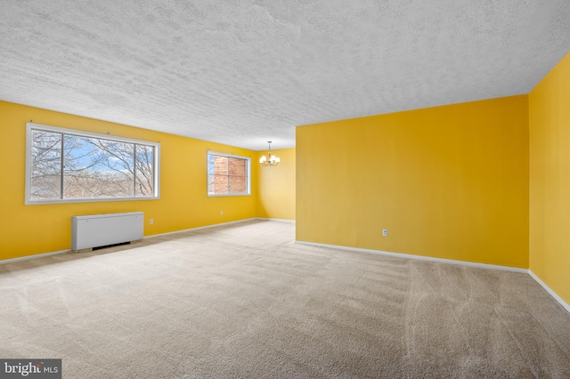 carpeted empty room with a notable chandelier and a textured ceiling