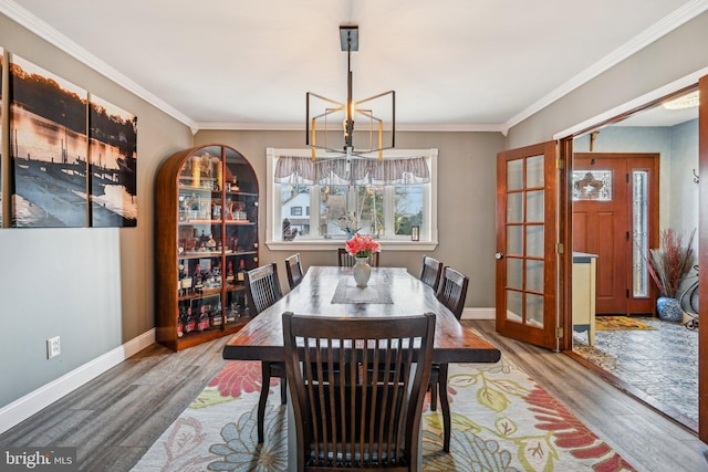 dining area featuring crown molding, wood-type flooring, and an inviting chandelier