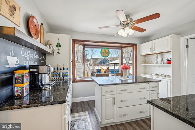 kitchen featuring tasteful backsplash, white cabinets, dark stone counters, a center island, and dark wood-type flooring