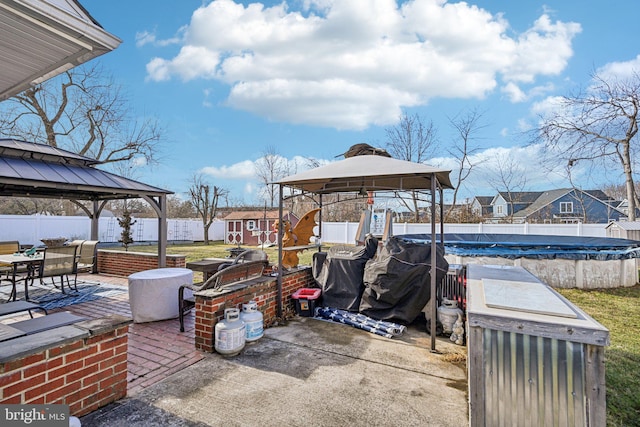 view of patio featuring a shed, a gazebo, and a covered pool