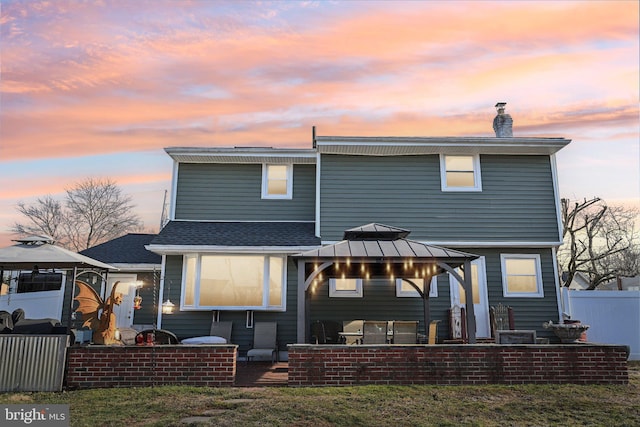 back house at dusk with a gazebo and a patio