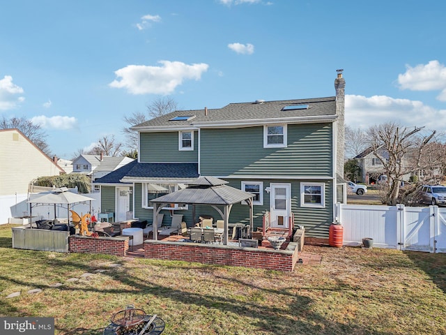 back of property with a gazebo, a fire pit, a lawn, and a patio area