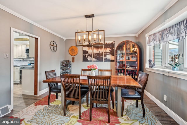 dining space with hardwood / wood-style flooring, crown molding, and an inviting chandelier