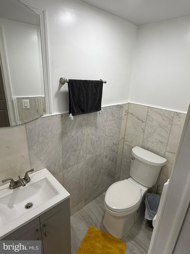 bathroom with vanity, toilet, and tile walls