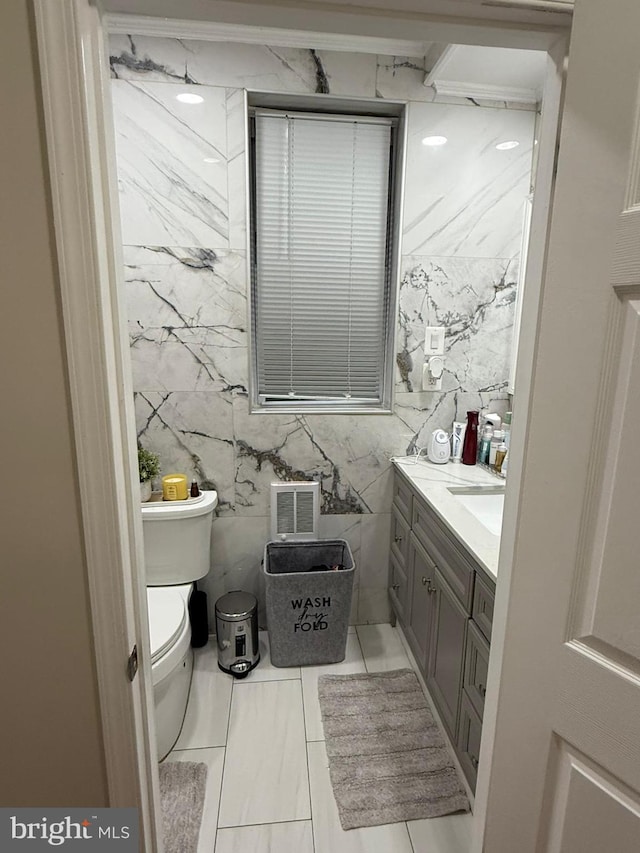 bathroom with tile walls, vanity, and toilet