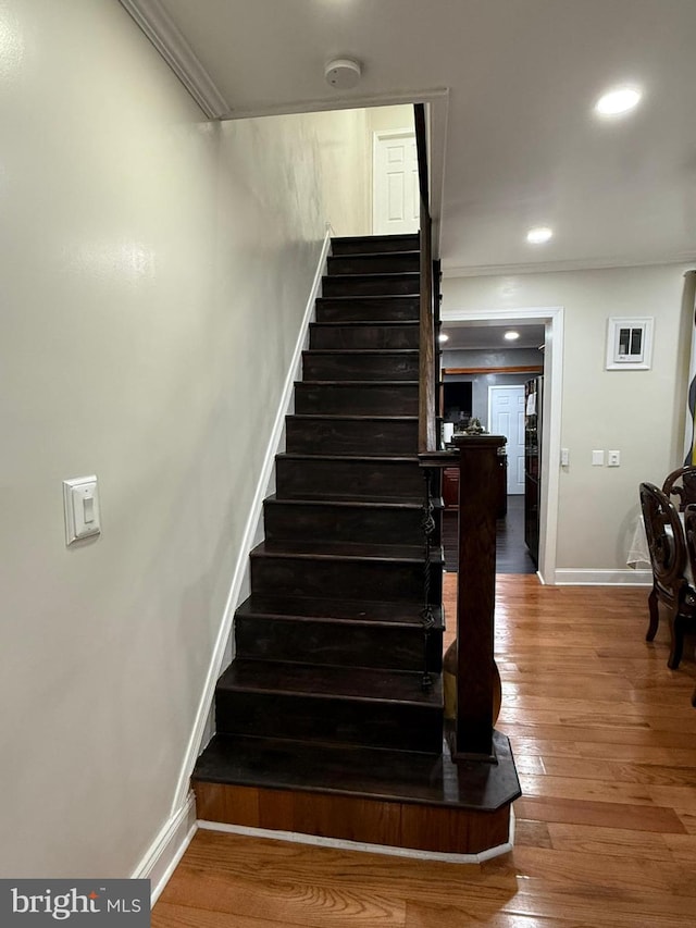 staircase featuring hardwood / wood-style flooring and ornamental molding