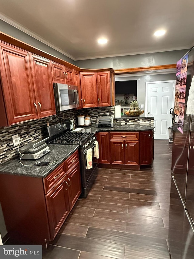 kitchen with dark hardwood / wood-style flooring, backsplash, dark stone countertops, and black gas stove