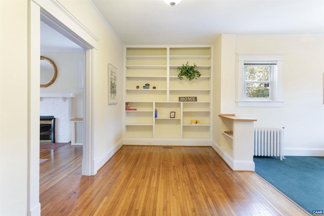 hall featuring radiator, crown molding, built in features, and hardwood / wood-style floors