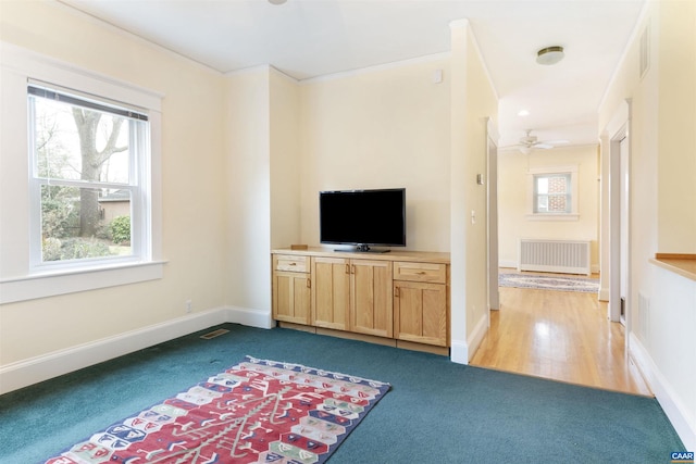 unfurnished living room featuring carpet, radiator, and ceiling fan