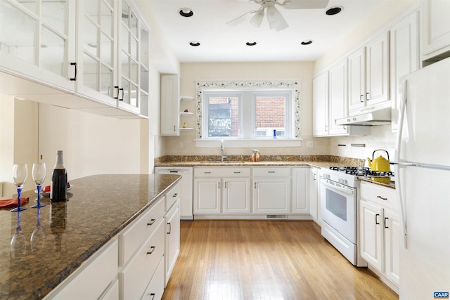 kitchen featuring sink, white appliances, dark stone countertops, light hardwood / wood-style floors, and white cabinets