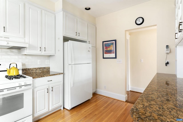 kitchen featuring white appliances, light hardwood / wood-style flooring, white cabinets, decorative backsplash, and dark stone counters