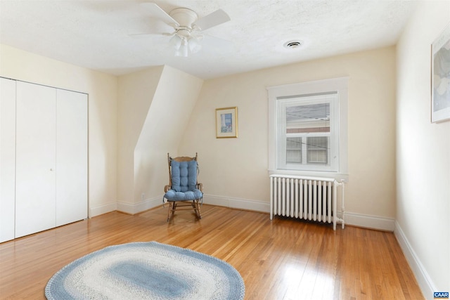 sitting room featuring hardwood / wood-style flooring, ceiling fan, radiator, and a textured ceiling