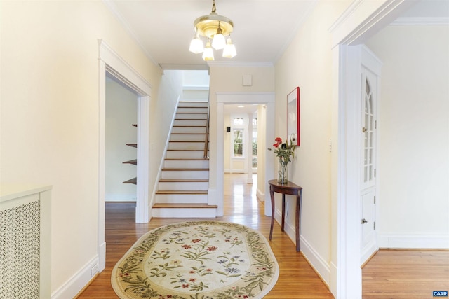 entrance foyer with hardwood / wood-style flooring, ornamental molding, radiator, and an inviting chandelier