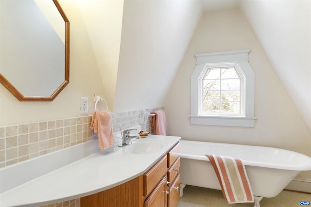 bathroom with lofted ceiling, vanity, and a tub