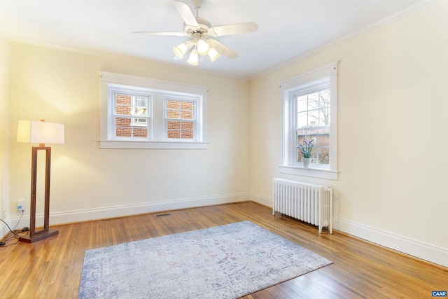 unfurnished room with radiator, ornamental molding, ceiling fan, and light wood-type flooring