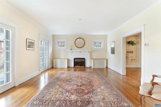 living room with hardwood / wood-style flooring, ornamental molding, radiator heating unit, and a fireplace