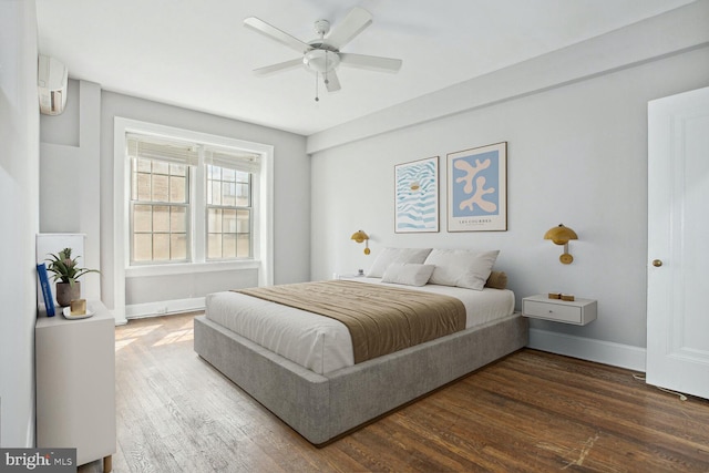 bedroom featuring ceiling fan, an AC wall unit, and dark hardwood / wood-style flooring