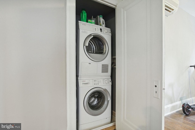 laundry area featuring hardwood / wood-style floors and stacked washer and clothes dryer