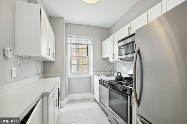 kitchen with light tile patterned floors, sink, appliances with stainless steel finishes, backsplash, and white cabinets