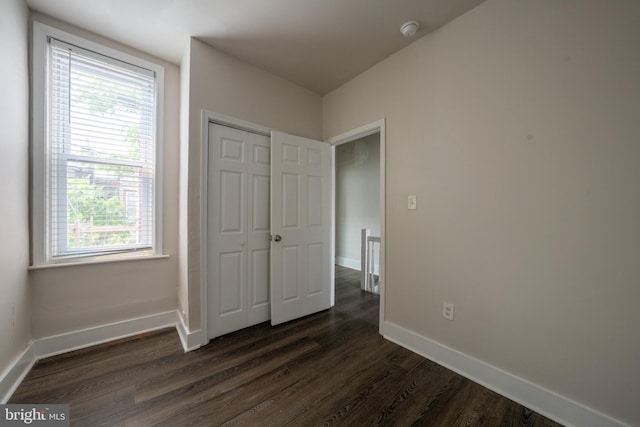 unfurnished bedroom featuring dark wood-type flooring and a closet