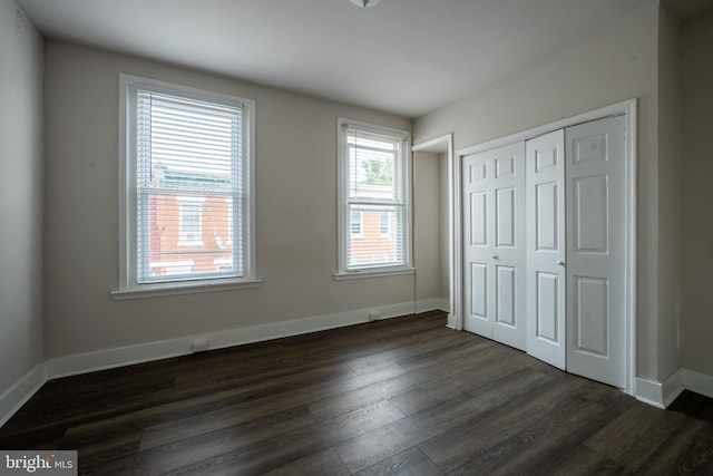 unfurnished bedroom with dark wood-type flooring and a closet