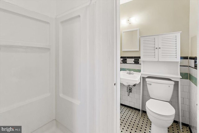 bathroom with tile walls and toilet