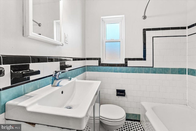 bathroom with sink, tile walls, a tub to relax in, tile patterned flooring, and toilet