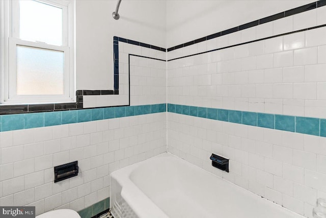 bathroom with a bathing tub and tile walls