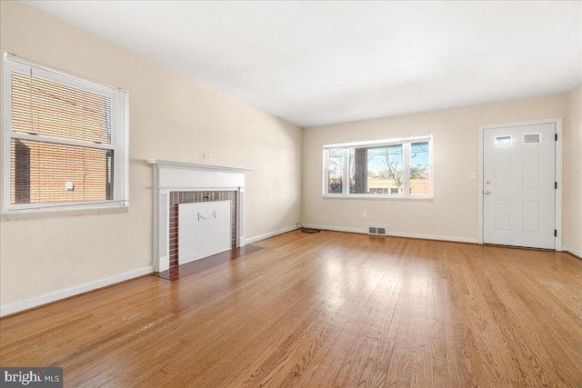 unfurnished living room featuring light wood-type flooring and a fireplace