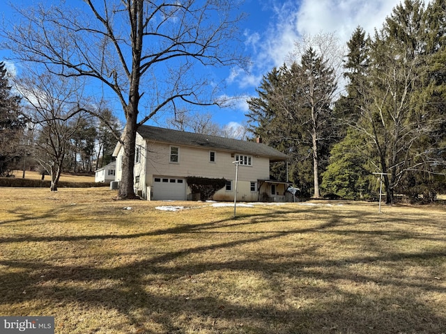 rear view of house with a garage and a lawn