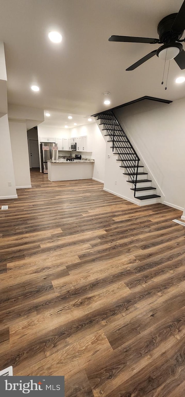 basement with dark wood-type flooring, stainless steel refrigerator, and ceiling fan