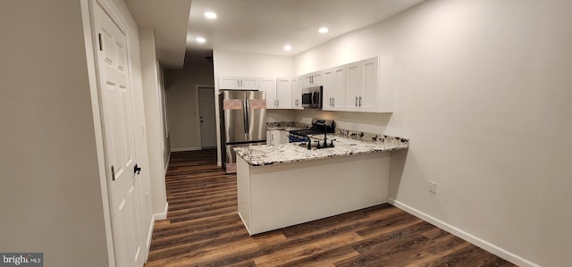 kitchen with dark wood-type flooring, appliances with stainless steel finishes, light stone countertops, and white cabinets