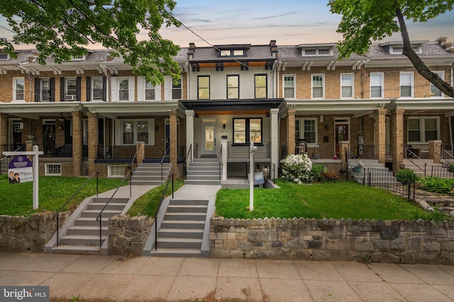 townhome / multi-family property with a yard and covered porch