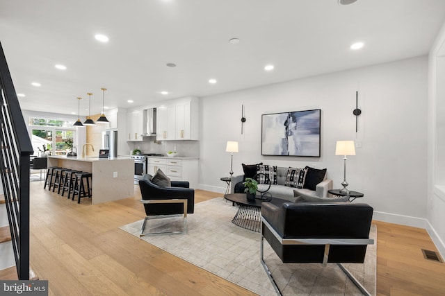 living room featuring sink and light hardwood / wood-style flooring