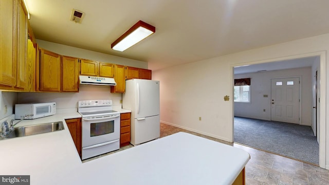 kitchen with light countertops, brown cabinetry, a sink, white appliances, and under cabinet range hood